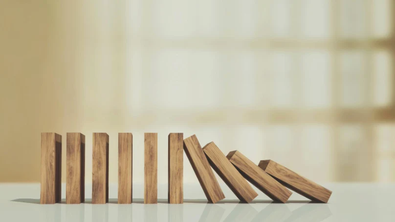 A stack of dominoes falling, symbolizing the cumulative effect of small habits