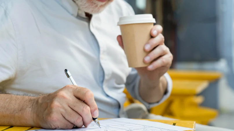 A teacher grading papers with a cup of coffee nearby.