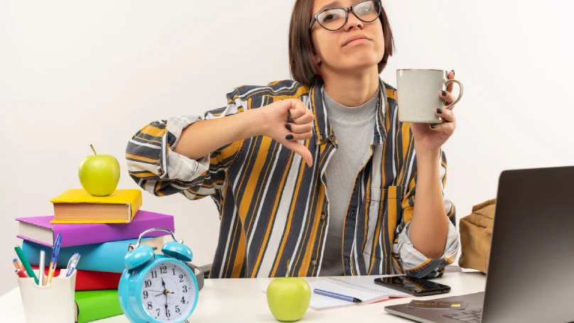 A teacher juggling multiple items like books, a clock, and a laptop