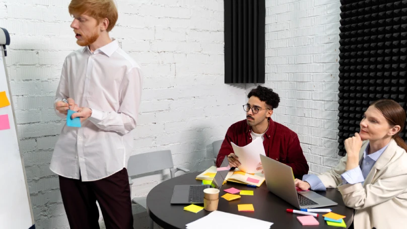 A team of employees gathered around a whiteboard, brainstorming goals.